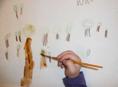 un enfant de maternelle en train de colorier au pinceau des crayons de couleur aquarellables