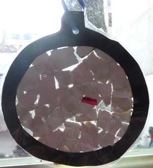 verso de la boule de noel faite avec un disque noir recouvert de papiers déchirés brillants