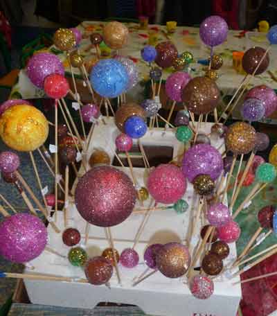 boules de Noël trempées dans de la peinture de toute les couleurs et des paillettes et mises sur des pics