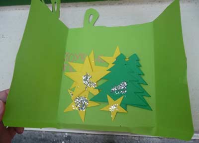 carte verte en forme de cadeau intérieur contenant des sapins et des étoiles
